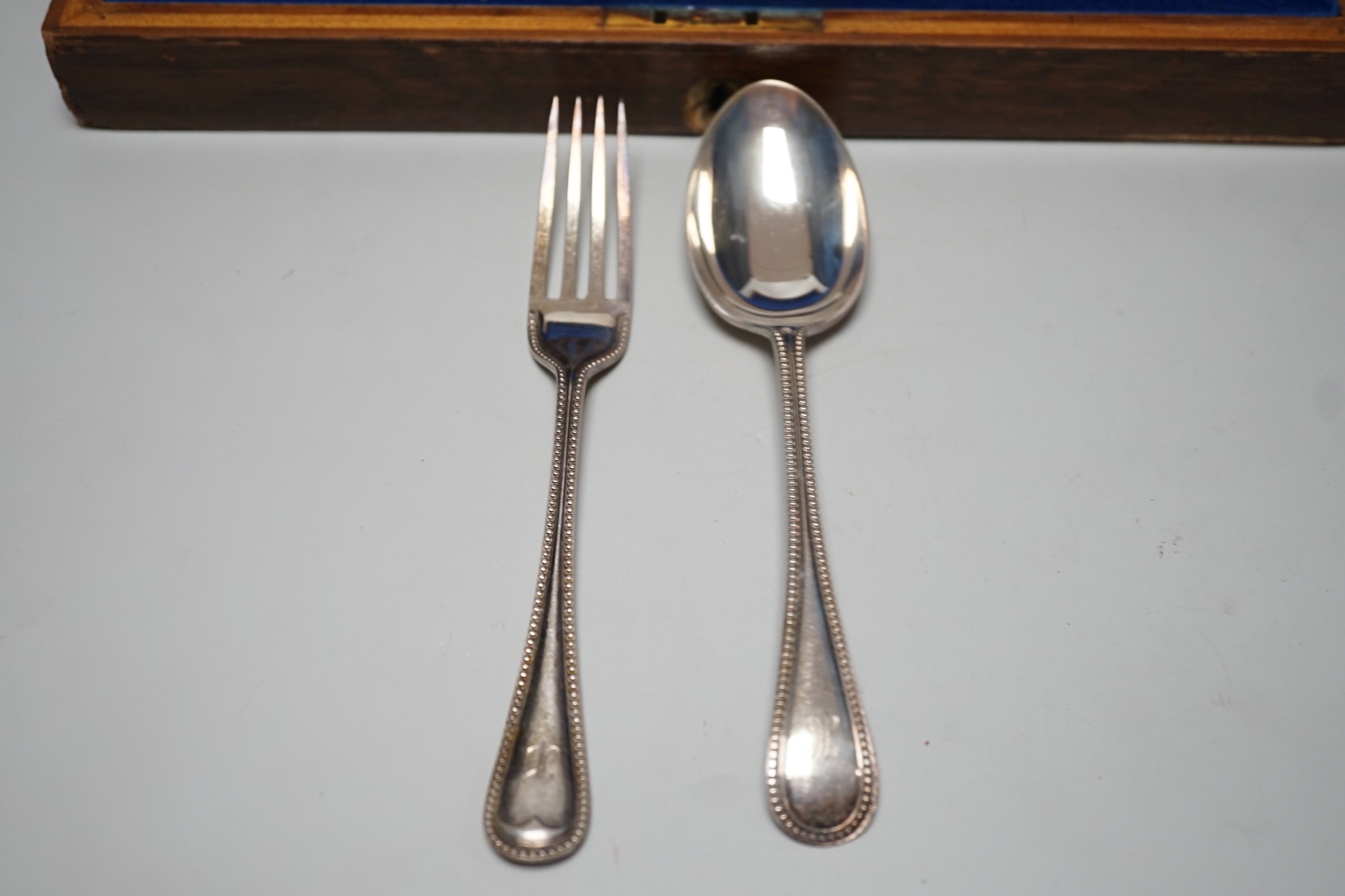 A set of twelve early 20th century silver beaded old English pattern dessert spoons Sheffield, 1908 & 1910 and twelve matching dessert forks, Sheffield, 1919, all by John Round & Sons, oak cased, 46.7oz